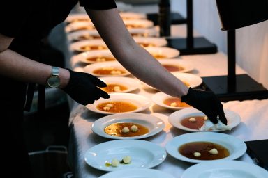 Anrichten 3 Servierender Angestellter platziert Butter auf Tellern mit Brühe.