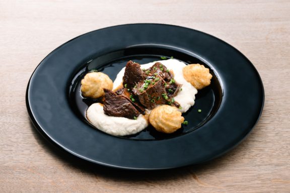 Rindfleischstücke auf cremigem Püree, garniert mit runden Lachshäppchen.