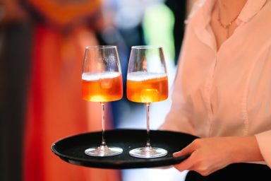 Service 2 Zwei Gläser mit orangefarbenem Getränk auf einem schwarzen Tablett.