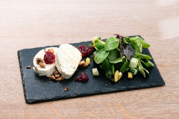 Ein Teller mit Käse, Granola, Preiselbeeren und einem frischen Salat.